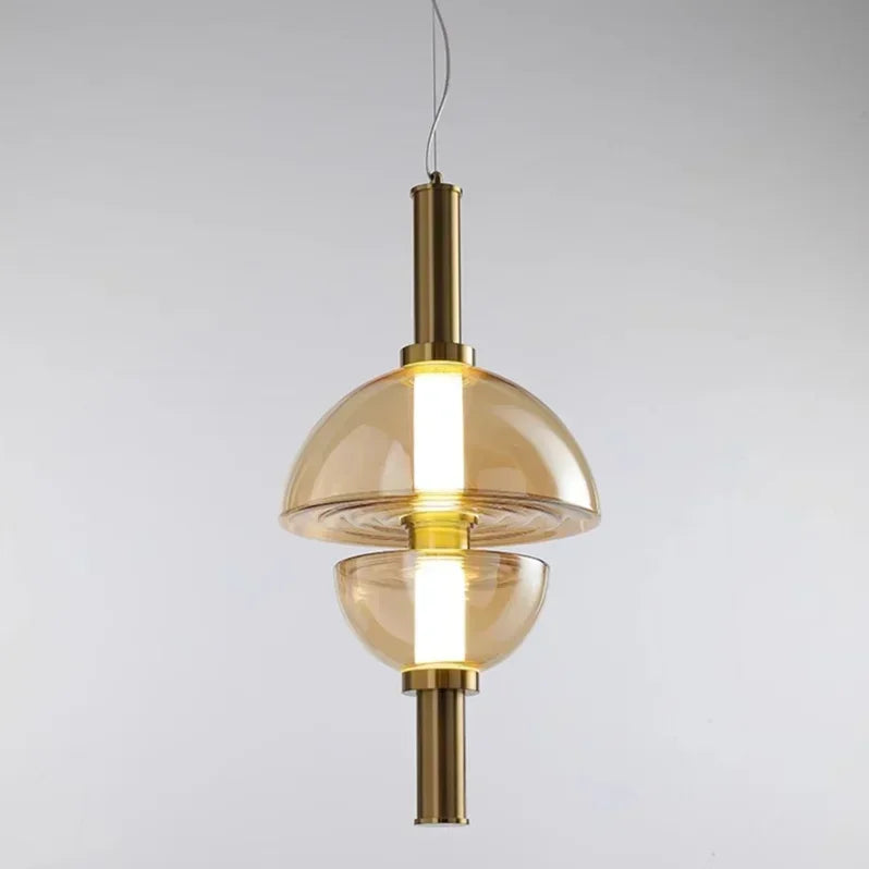 The Clérachic glass pendant in amber glass on a brass stem, dome above a rounded lower bowl.