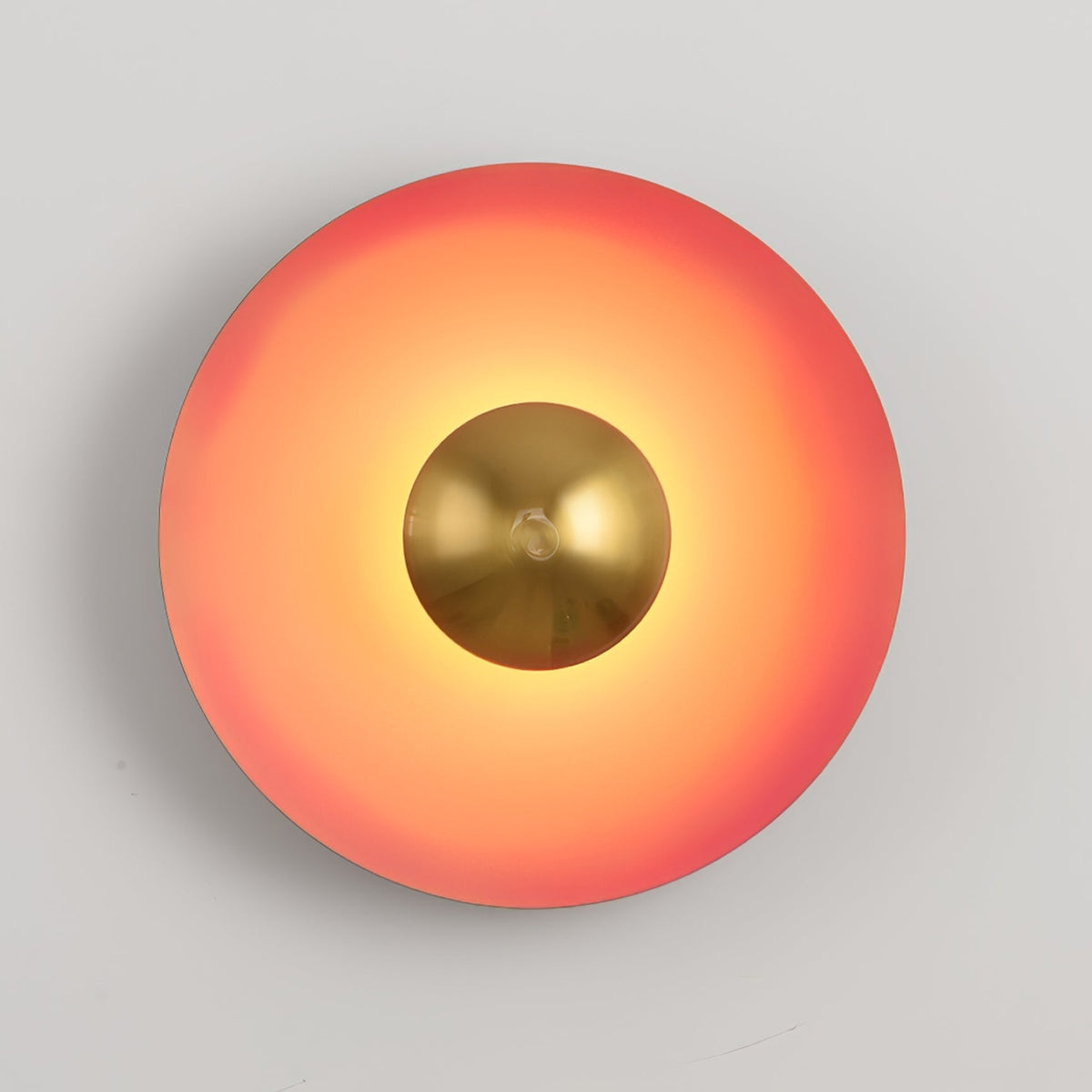 Warm light spreads from the antique copper centre of this coral-orange Clérachic wall light, on grey.