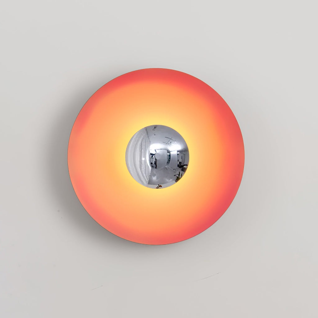 The mirrored centre of this coral-orange Clérachic wall light reflects the studio setting, shown on grey.