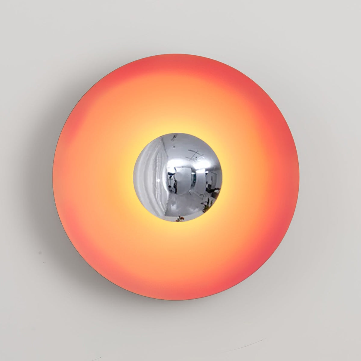The chrome centre of this coral-orange Clérachic wall light reflects a soft highlight, shown on grey.