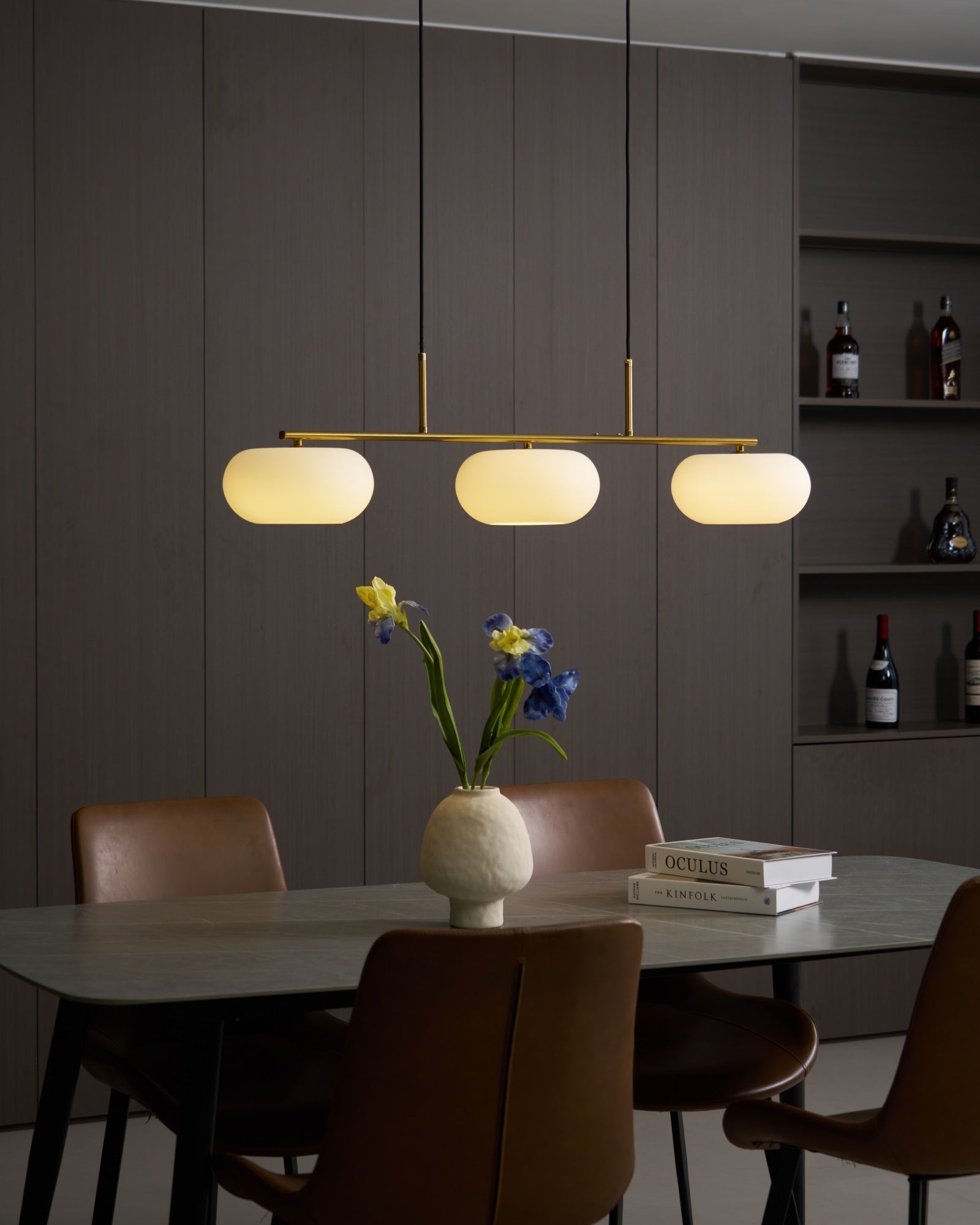 Three white globe shades evenly spaced on a pendant bar