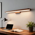 The bar light lit above a walnut desk with a laptop and open book, mirror edge visible at the left.