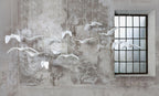 White bird-shaped pendants from this Clérachic fixture hang against a weathered plaster wall beside a paned window.
