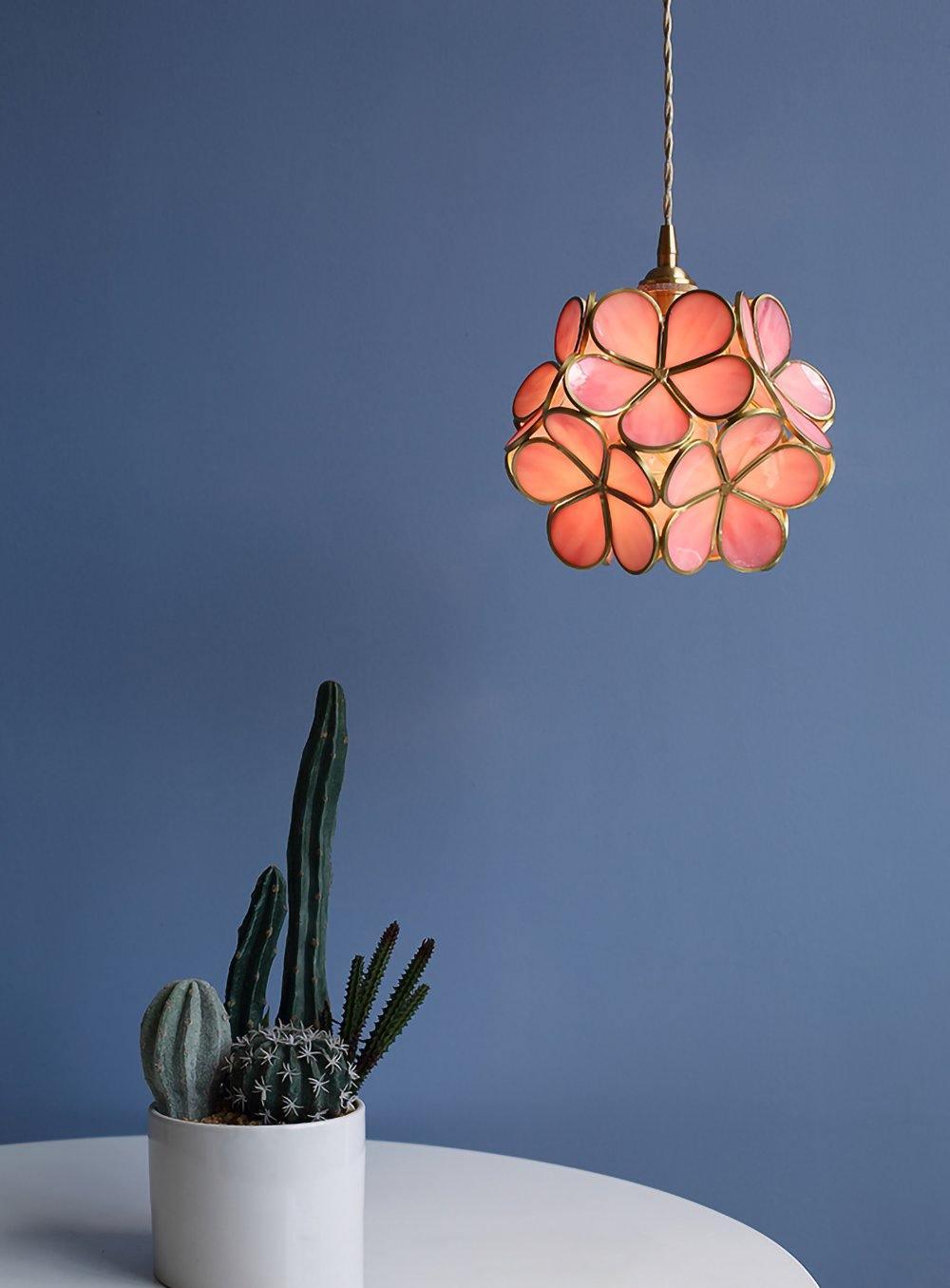 Pink glass petal pendant light softly glowing above a table