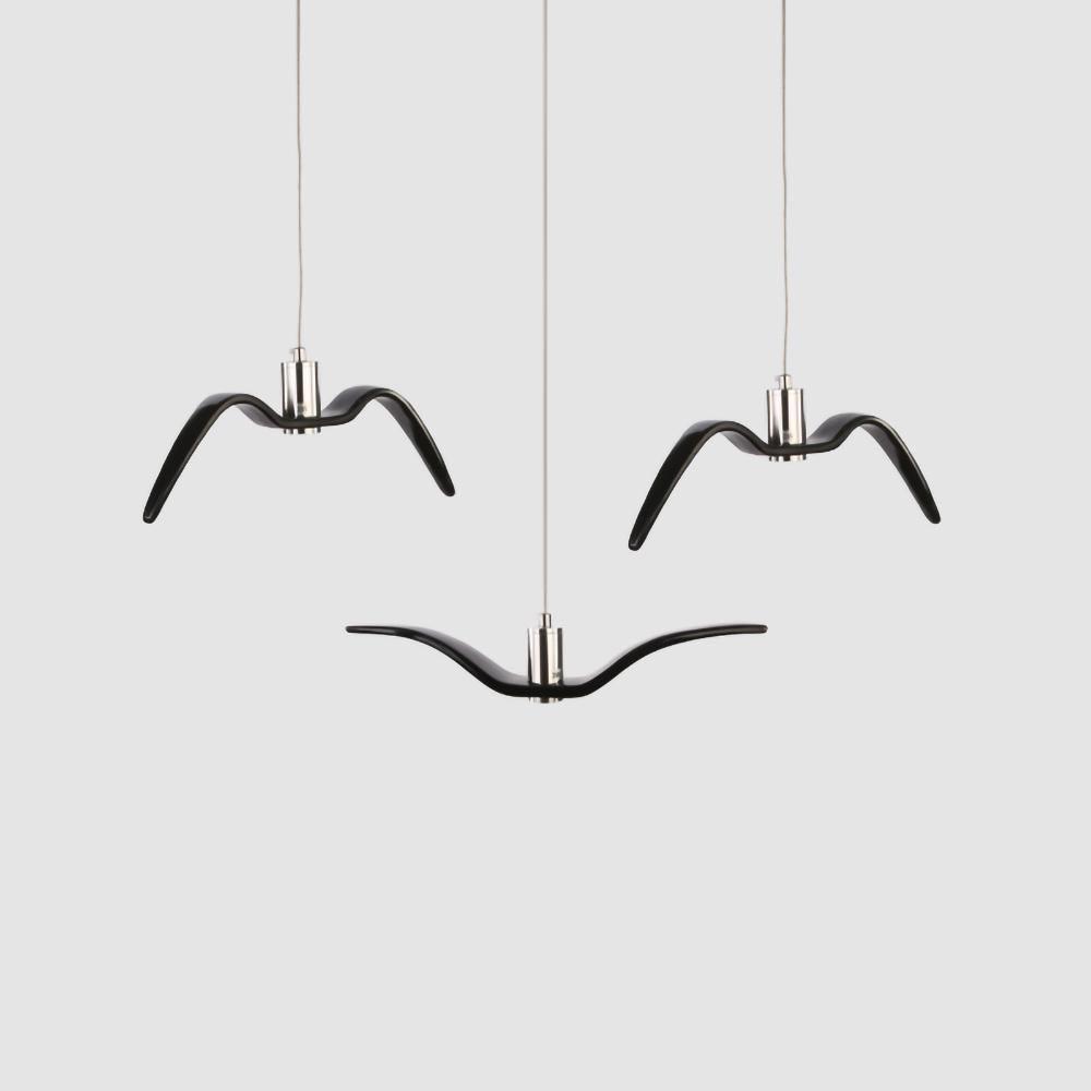 Three black bird-shaped pendants from this Clérachic fixture hang together against a plain light-grey backdrop.