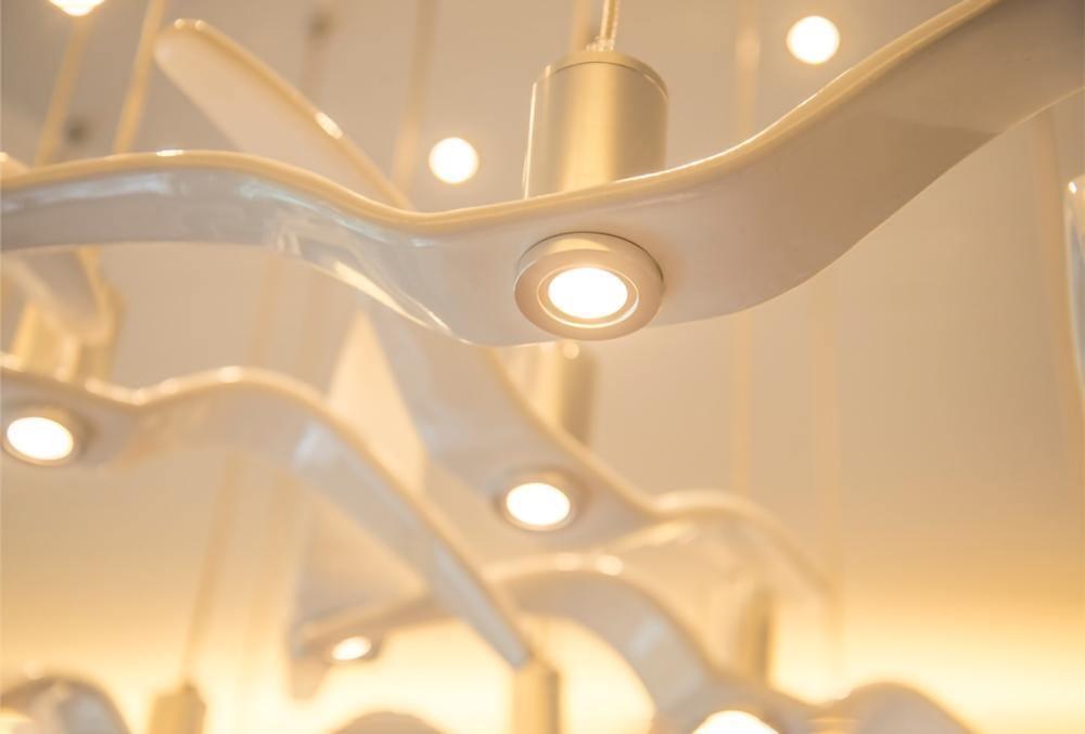 Close view of the underside of a resin wing on this Clérachic pendant, its LED strip glowing warm.