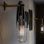 Glass wall lamp with slim arm glowing in a styled interior