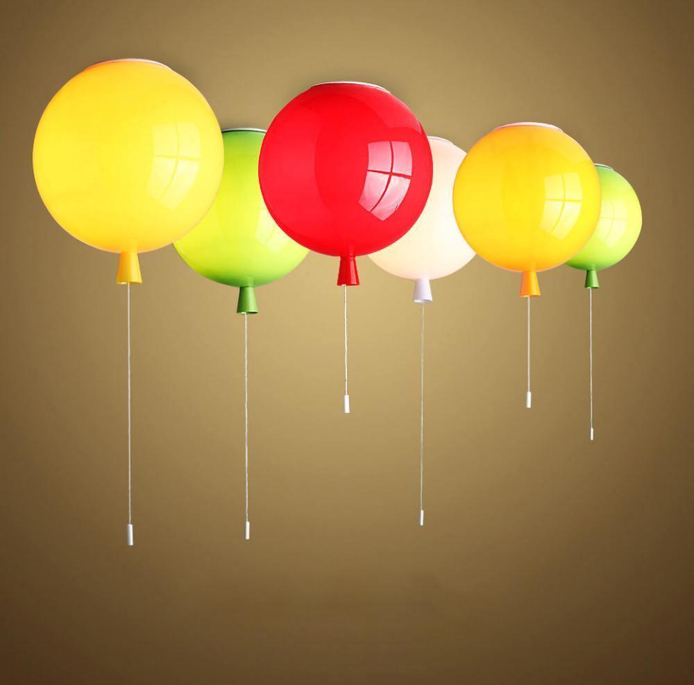 Six Clérachic balloon lights in yellow, green, red and orange float together against a warm golden-brown backdrop.