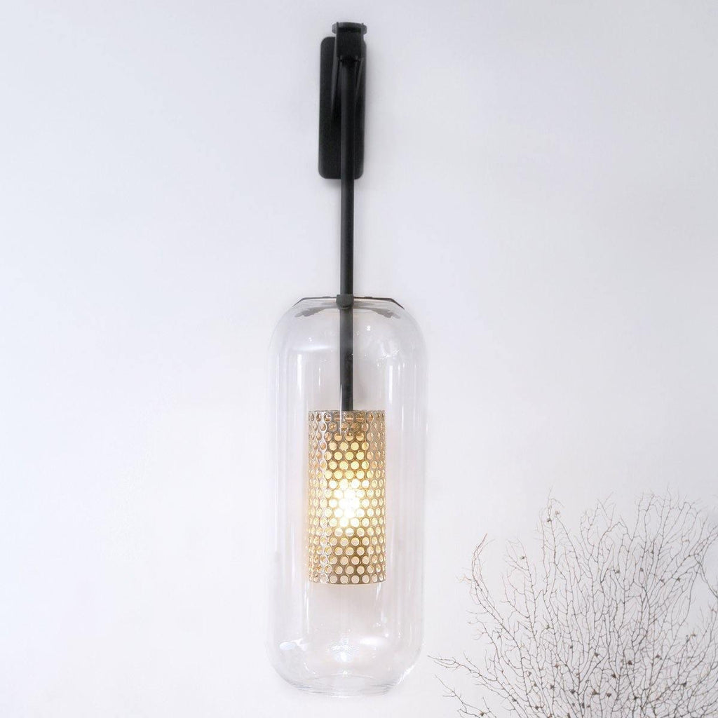 Glass wall lamp with metal arm glowing softly in a living room
