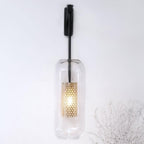 Glass wall lamp with metal arm glowing softly in a living room