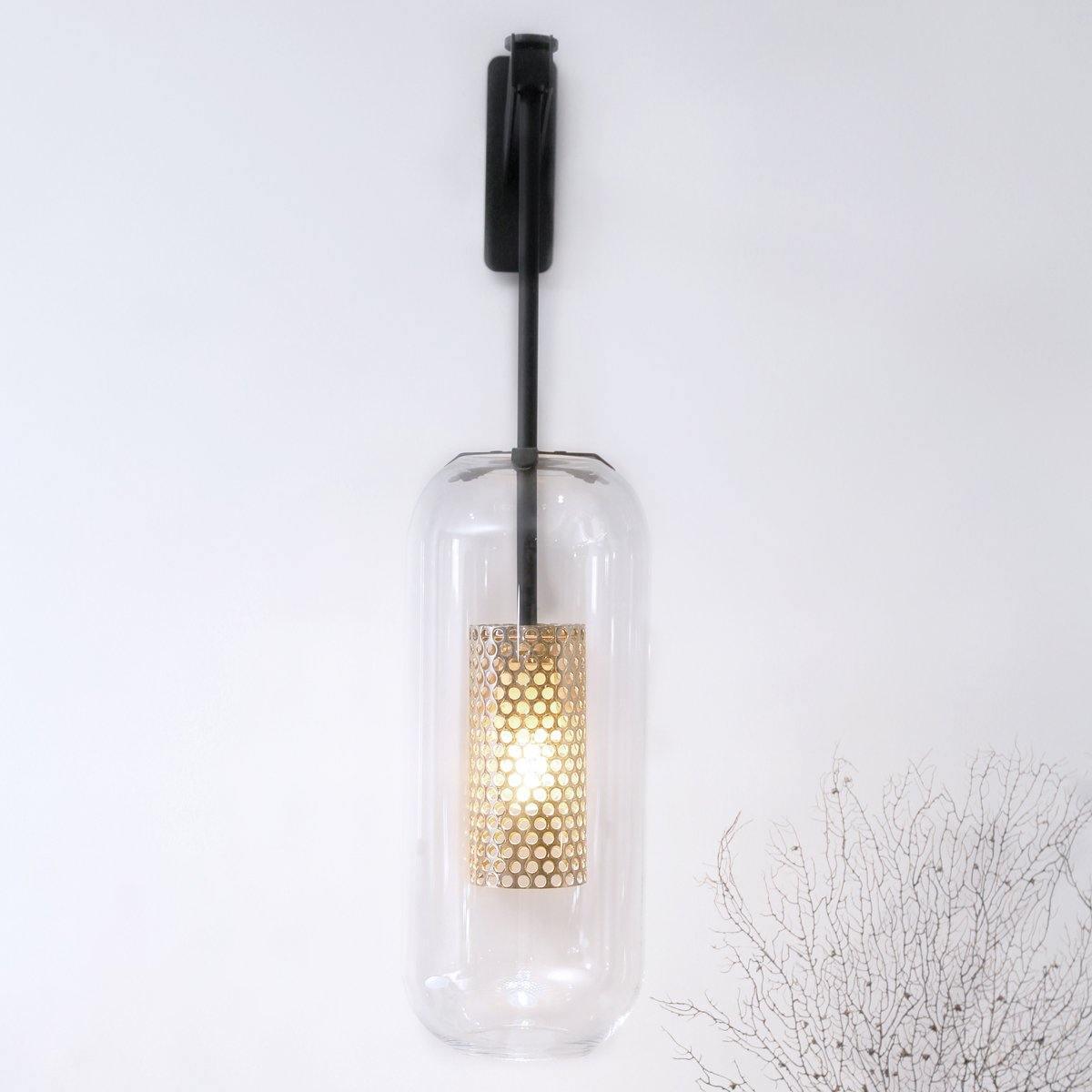 Glass wall lamp with metal arm glowing softly in a living room