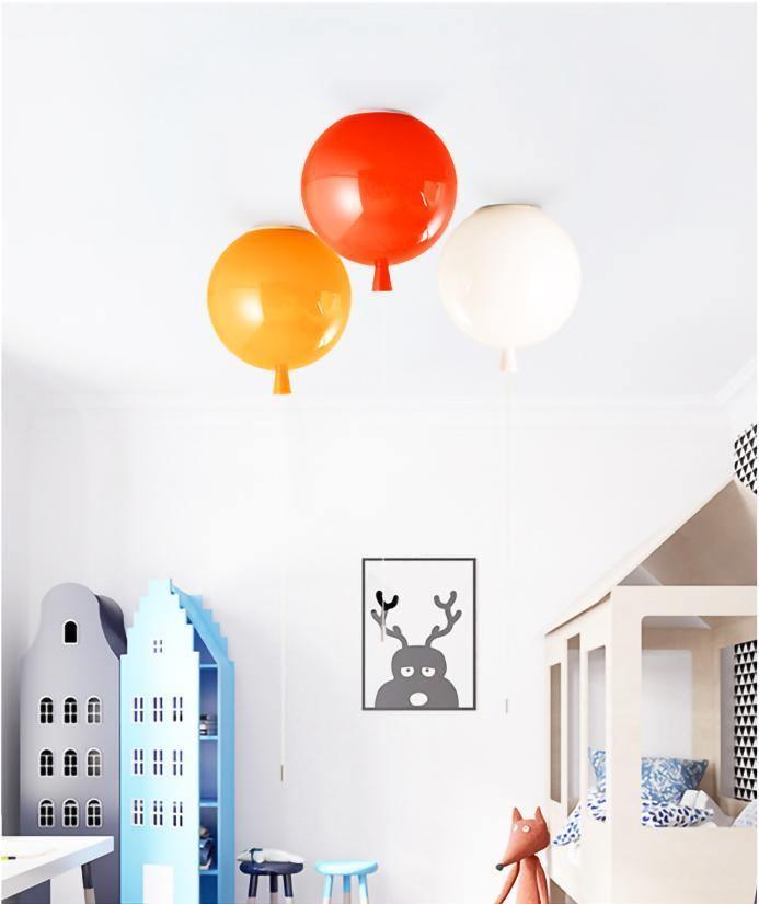 In a child's room with a toy house shelf, three Clérachic balloon lights in red, orange and white hang from the ceiling.