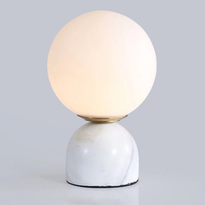 Sylas marble table lamp with a glowing white glass orb shade