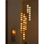 Three Clérachic alabaster sphere pendants hang together near a striped wall sconce in a dim room.