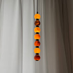 Close view of the alabaster spheres on this Clérachic pendant, their veining warmly lit against a sheer curtain.