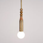 Detail shot of the Clérachic pendant's marble beads and leather wrap, with the bare bulb glowing beneath them.