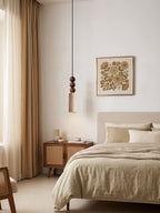 This Clérachic pendant lights a bedroom corner with a cane nightstand, an armchair and a gold floral print on the wall.