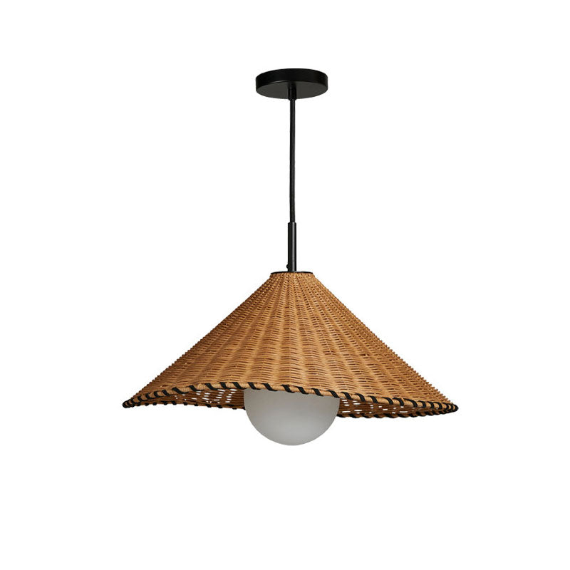 This Clérachic pendant hangs lit against a plain background, its woven rattan cone catching the light.
