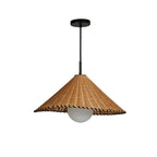 This Clérachic pendant hangs lit against a plain background, its woven rattan cone catching the light.