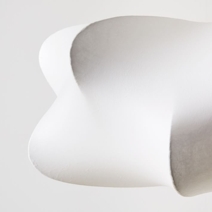 Cloud-shaped silk pendant light glowing over a table