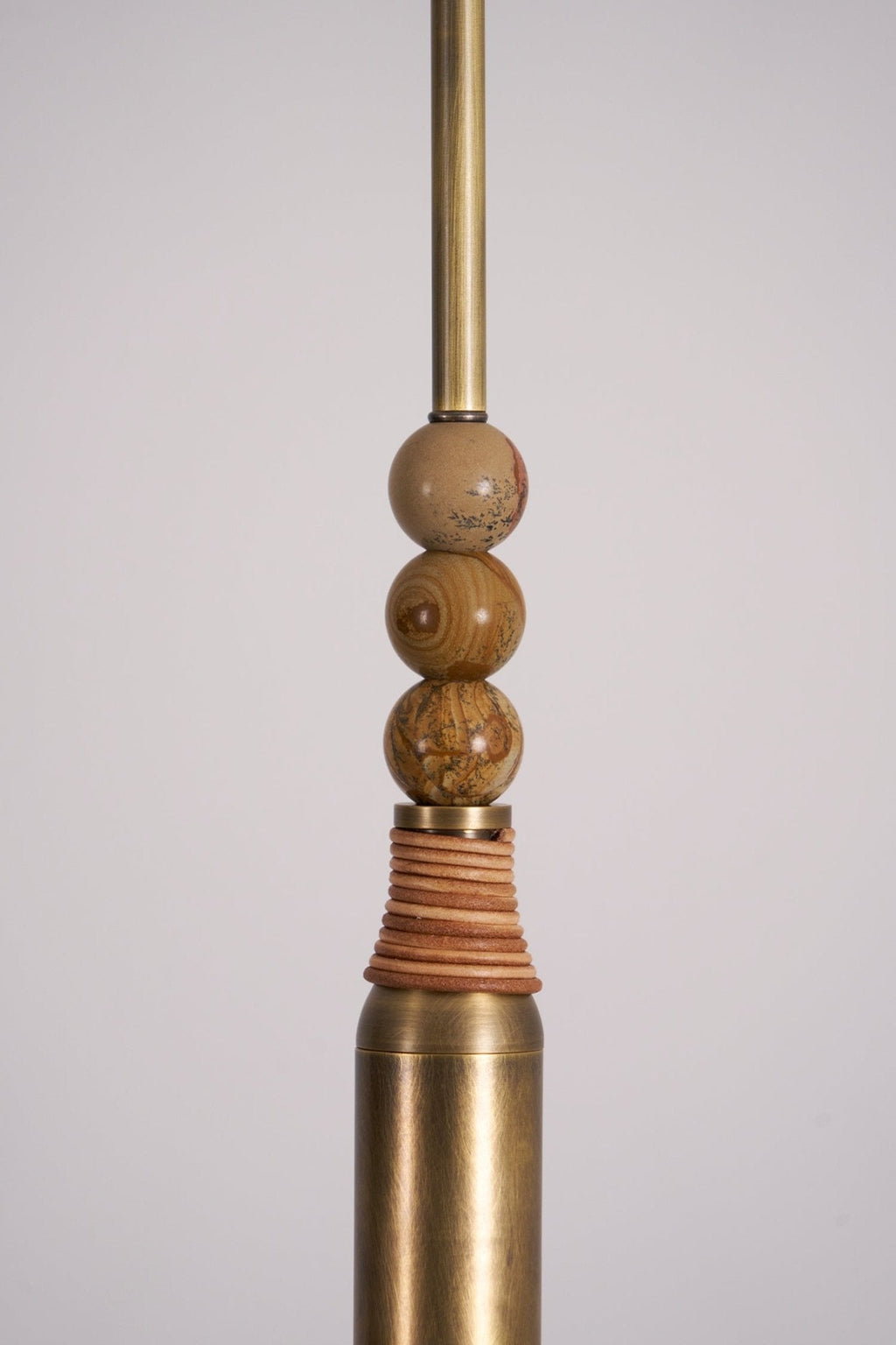 Close-up of the stacked marble beads and leather-wrapped brass sleeve on this Clérachic pendant light's drop rod.