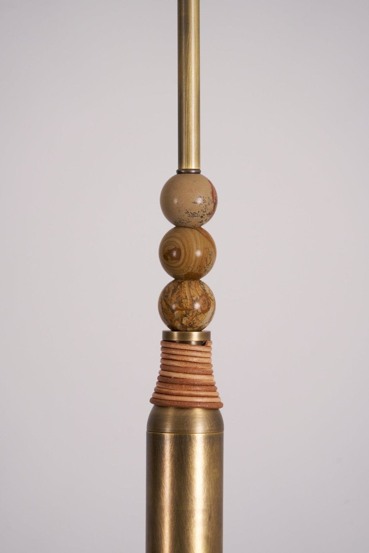 Close-up of the stacked marble beads and leather-wrapped brass sleeve on this Clérachic pendant light's drop rod.