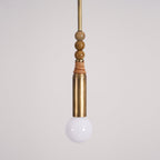 A closer view of the Clérachic pendant's marble bead stack and brass socket, with the frosted bulb glowing below.