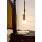 A bedroom view of the Clérachic marble-bead pendant light hanging over a nightstand, its drawer pull just visible below.