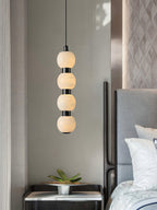 Close-up of a four-ball Orbique pendant lit in a bedroom, showing the veining in each alabaster sphere