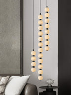 Three Orbique drops at staggered heights against a textured grey wall beside a low leather sofa