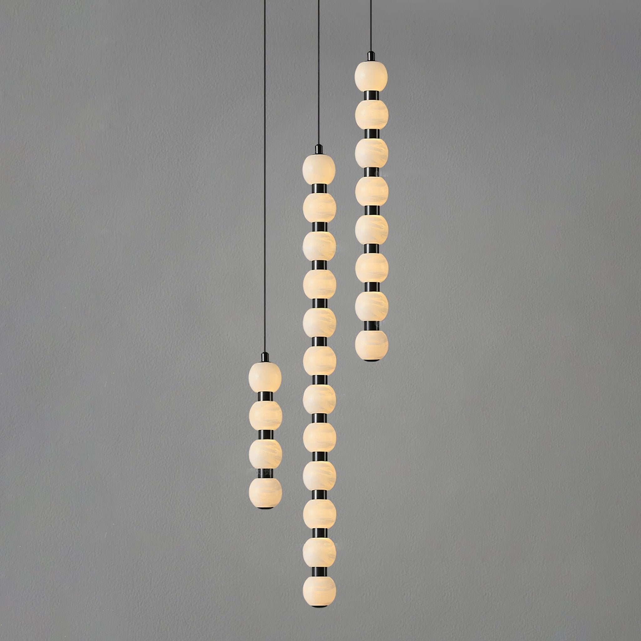 Four, twelve and eight-ball Orbique pendants lit together against a plain grey backdrop