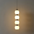 Four-ball Orbique pendant lit in a dark room, throwing a warm pool of light across the wall