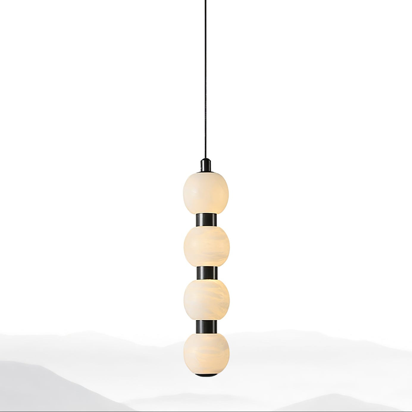 Four-ball Orbique pendant lit above a soft grey wash, seen against a clean white backdrop
