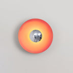 A closer crop shows the chrome centre of this coral-orange Clérachic wall light catching a highlight.