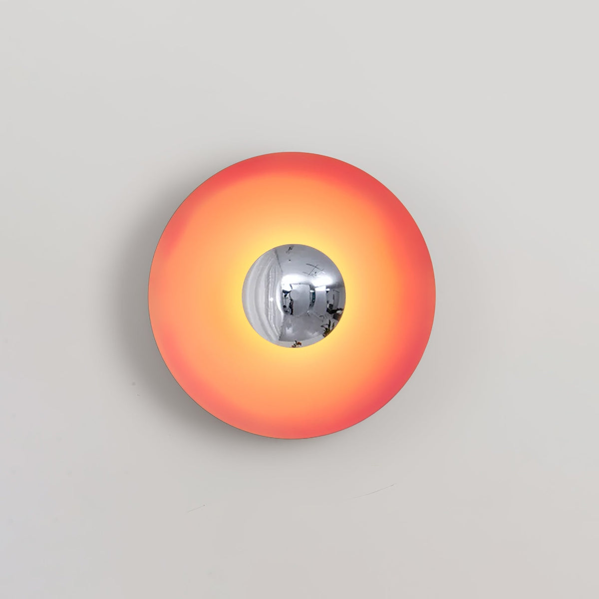 A closer crop shows the chrome centre of this coral-orange Clérachic wall light catching a highlight.