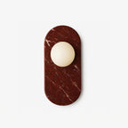 An opal glass sphere set into a deep red marble oval, the Clérachic wall sconce photographed flat against white.