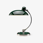 A green Clérachic desk lamp with a chrome curved stem, shown unlit on a plain white backdrop.