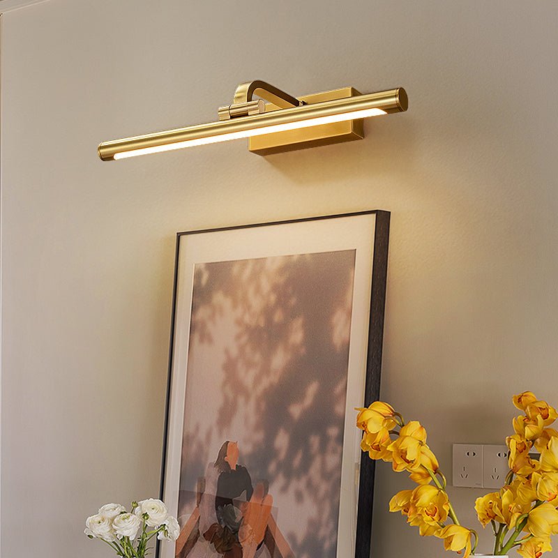 Gold wall light glowing softly over artwork in a styled room