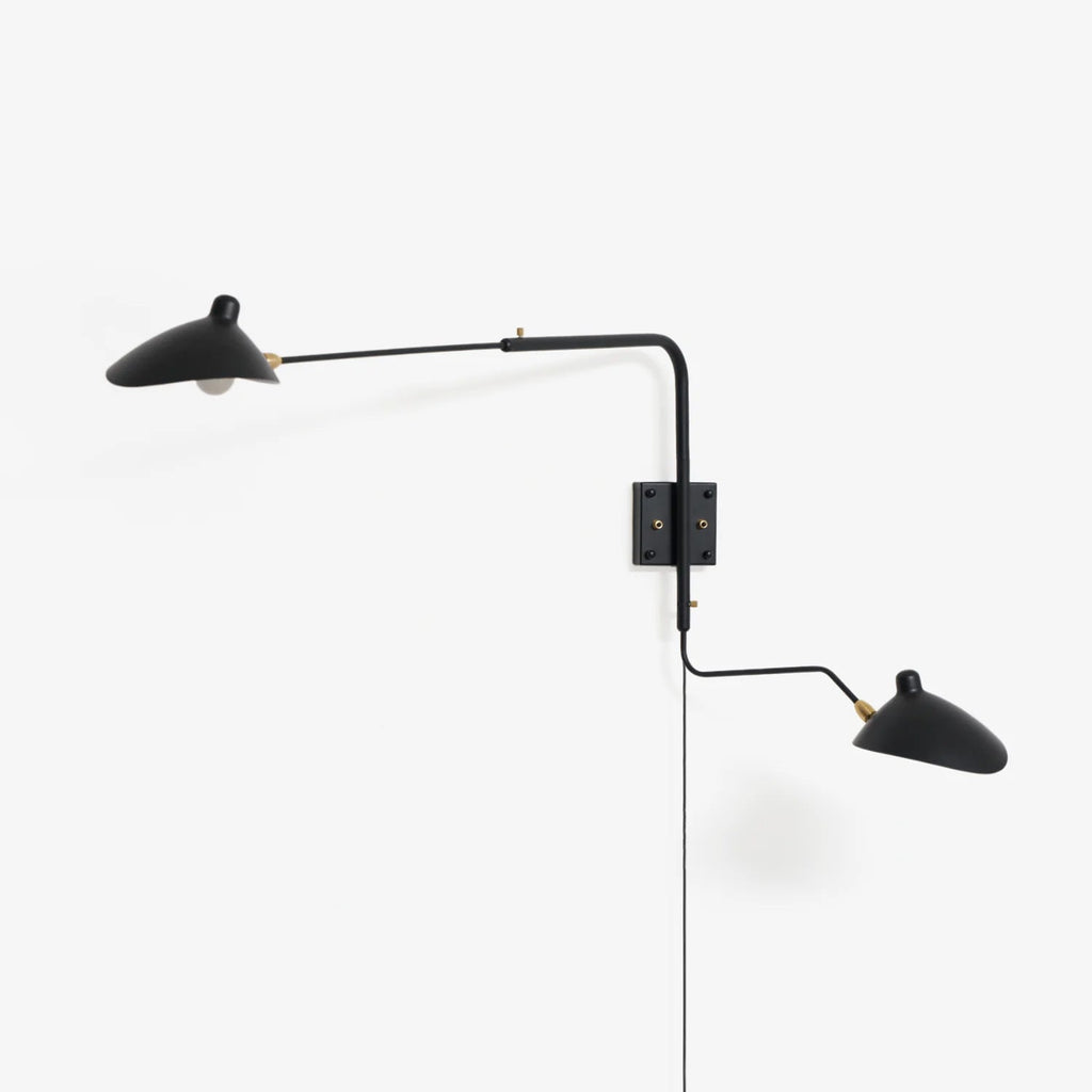 Wall sconce arm and shade detail against a pale interior wall