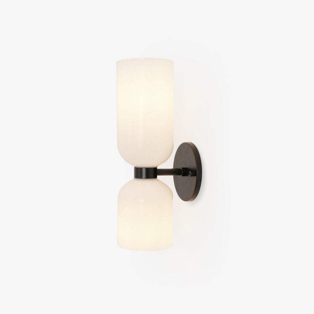 Two opal glass shades sit on this Clérachic wall light's matt black arm against a plain white backdrop.