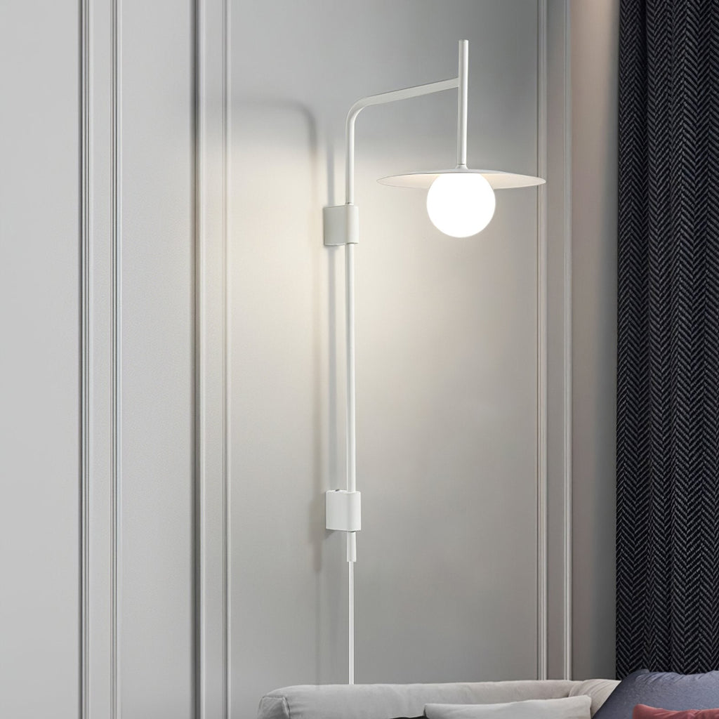 Swing arm wall lamp with frosted glass shade beside a bed