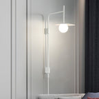 Swing arm wall lamp with frosted glass shade beside a bed