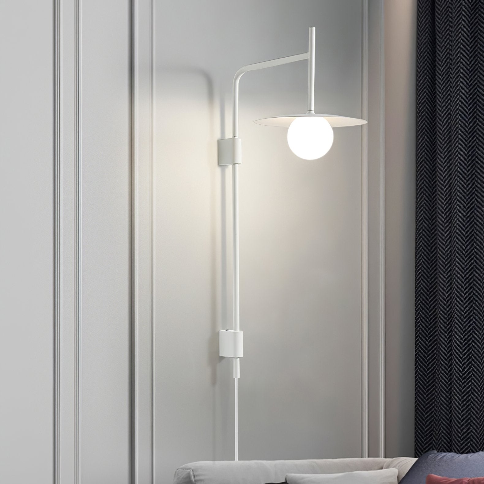 Swing arm wall lamp with frosted glass shade beside a bed