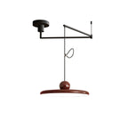 Swing arm pendant light with slim disc balanced over a dining table
