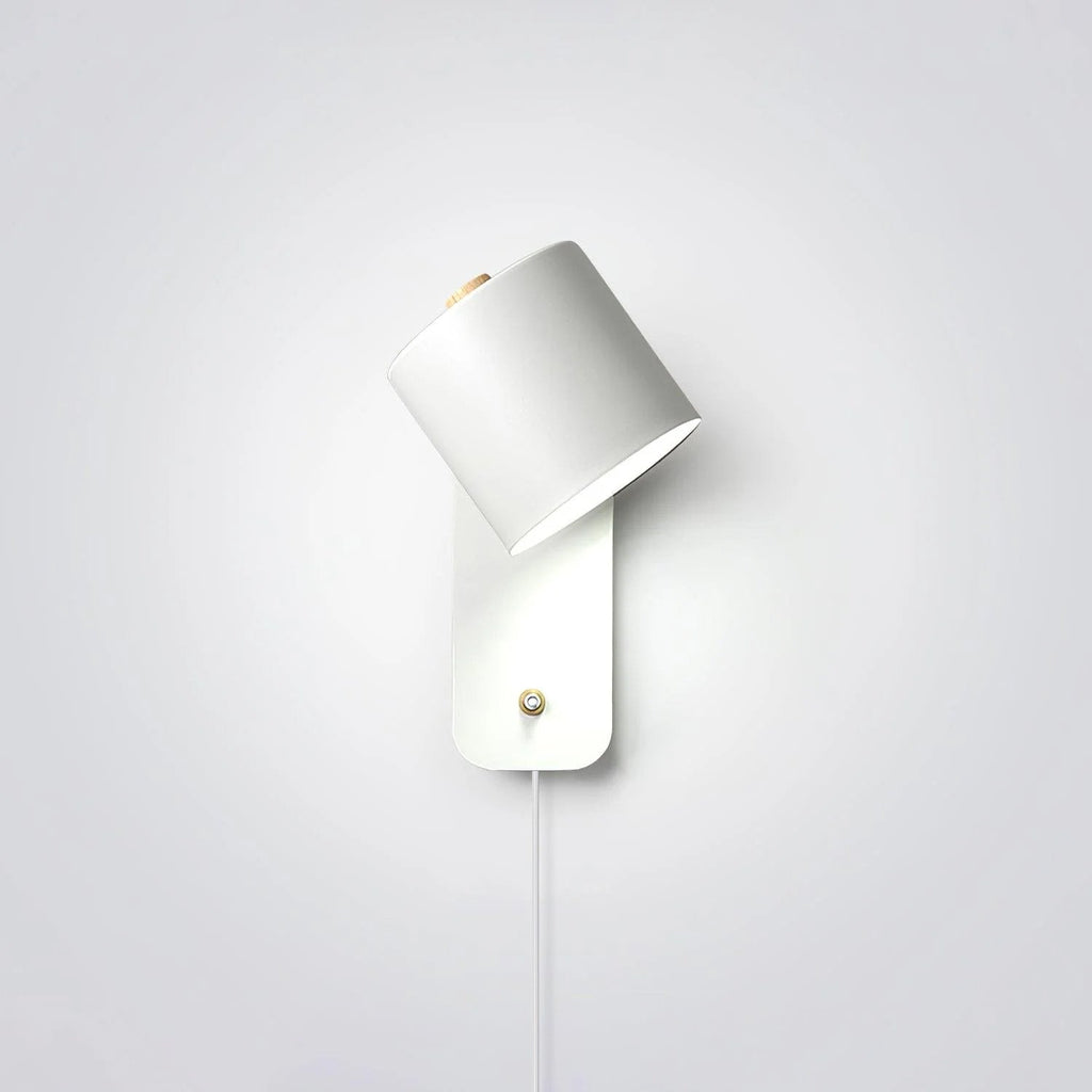 Cylinder wall lamp with rotatable shade mounted on a bedroom wall