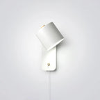 Cylinder wall lamp with rotatable shade mounted on a bedroom wall