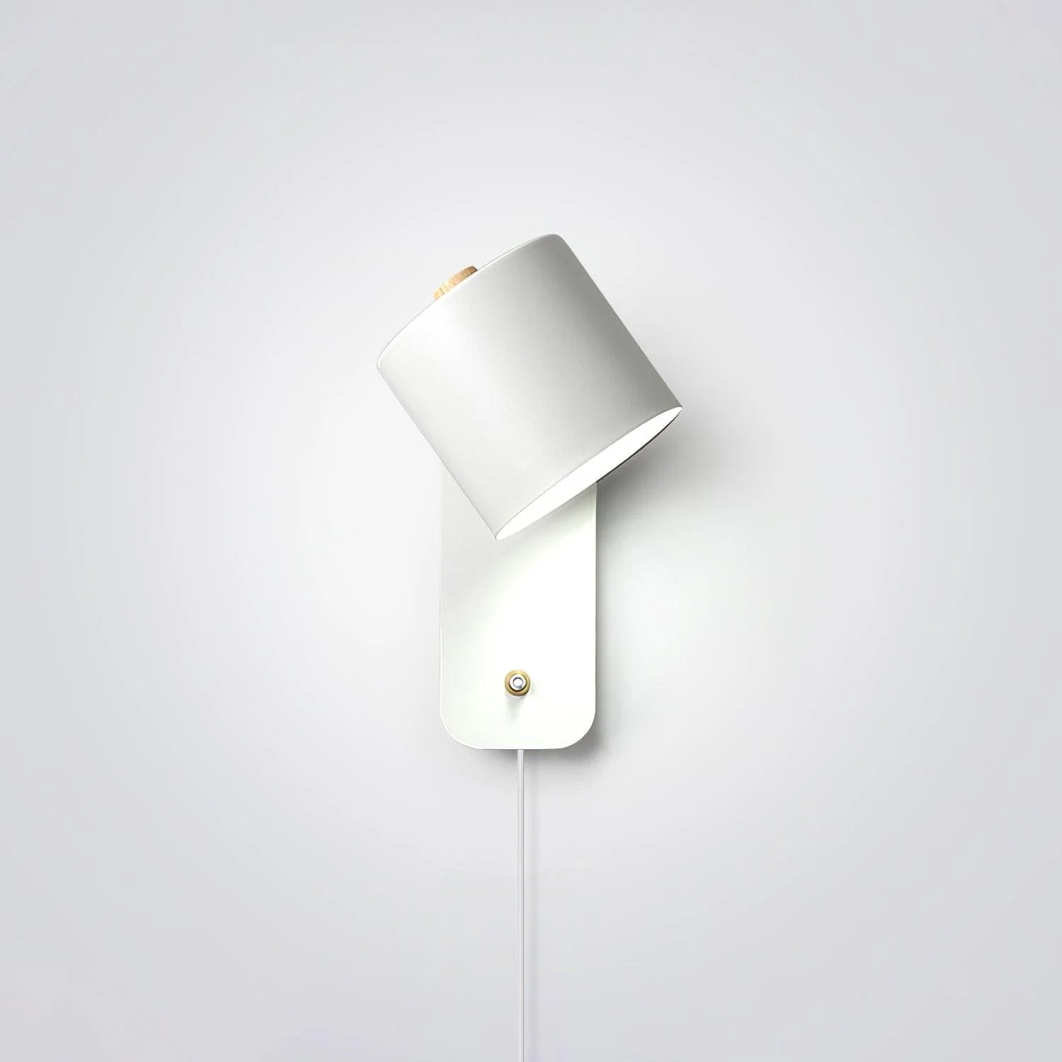 Cylinder wall lamp with rotatable shade mounted on a bedroom wall
