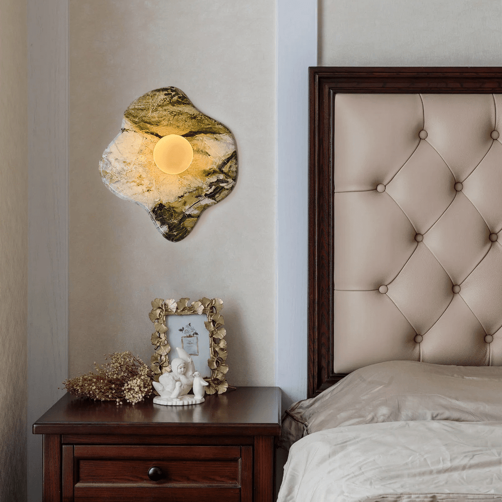 Above a dark wood nightstand holding a framed photo and small figurine, this Clérachic wall light glows beside a tufted headboard.