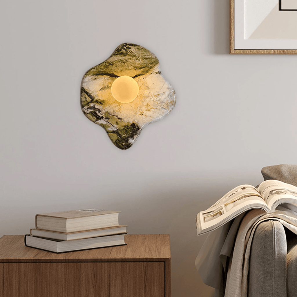 Mounted above a wooden console stacked with books and a folded throw, this Clérachic wall light glows beside a framed print.