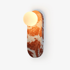 Clérachic wall light with a deep red marble body and a round glass shade, photographed straight on a white background.